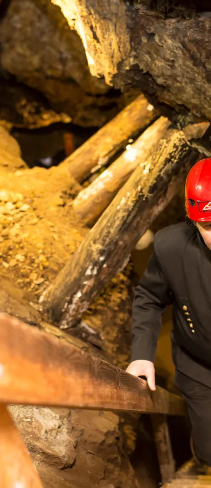 Miner in red helmet climbing wooden stairs inside historic underground mine
