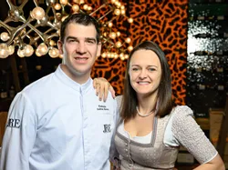 Smiling couple in traditional attire and chef uniform at upscale restaurant