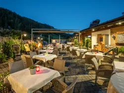 Gemütliche Restaurantterrasse in den Bergen mit Kerzen auf den Tischen bei Abenddämmerung