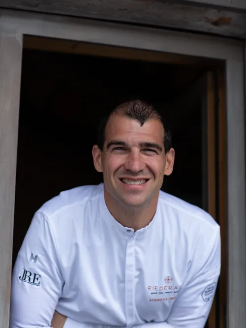 Smiling chef in white uniform leaning out of a window