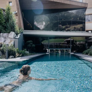 Frau schwimmt in einem luxuriösen Außenpool eines modernen Wellnesshotels