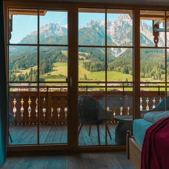 Cozy hotel room with mountain view through wooden balcony window in alpine region