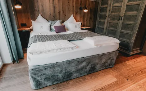 Gemütliches Hotelzimmer mit Doppelbett, Holzverkleidung und Kleiderschrank