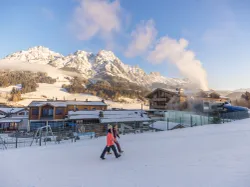 Winterresort in den Alpen mit Spaziergängern im Schnee und Bergblick im Hintergrund