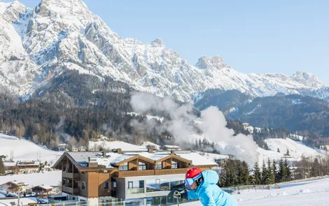 Skifahrer zieht Schwung auf präparierter Piste vor schneebedeckten Alpen und Chalets