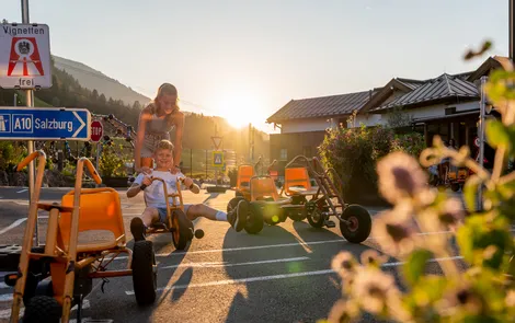 'Good Life' family week discounts Children playing with pedal go-karts on a sunny day in Salzburg outdoor area