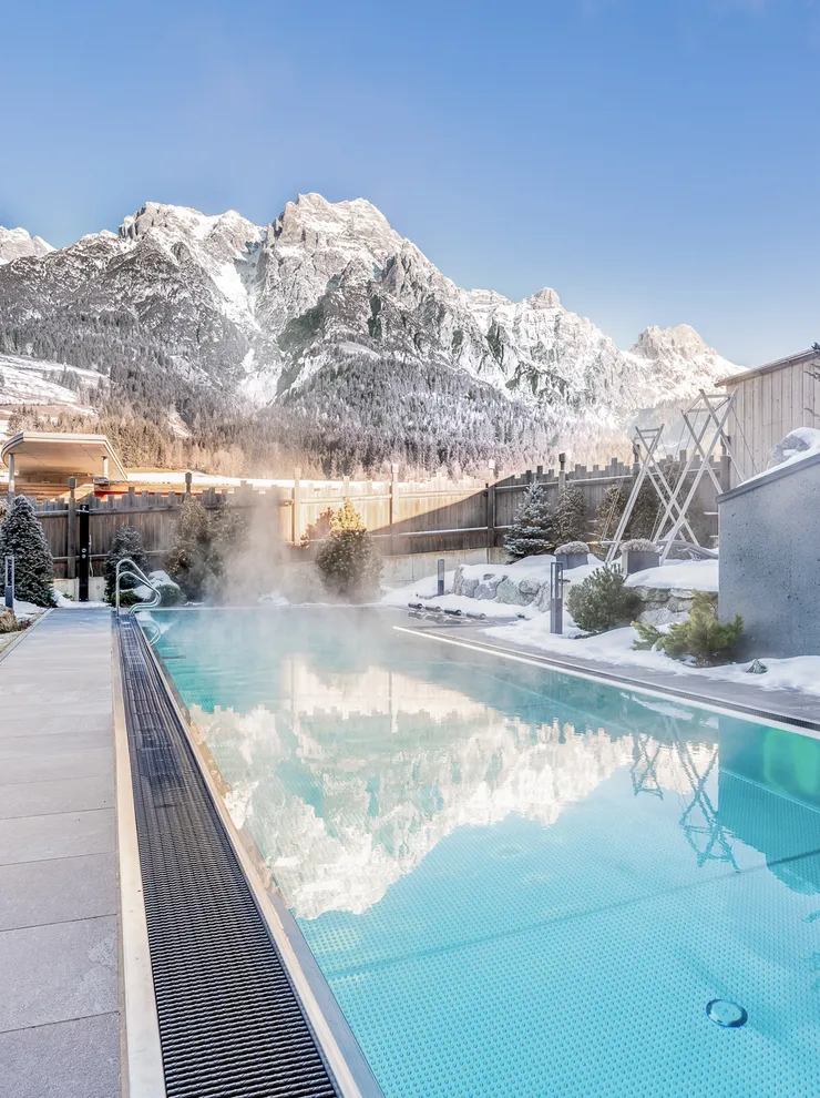Outdoor heated pool in snowy alpine resort with mountain view