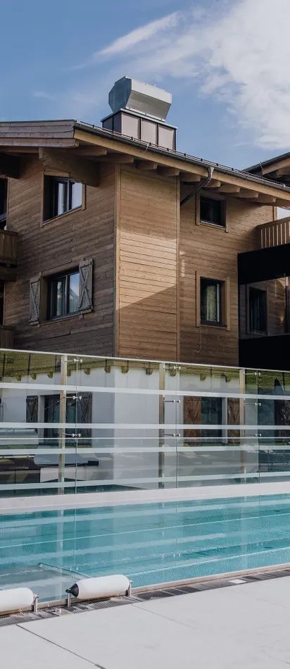 Modern wellness hotel with outdoor pool and mountain views in alpine setting