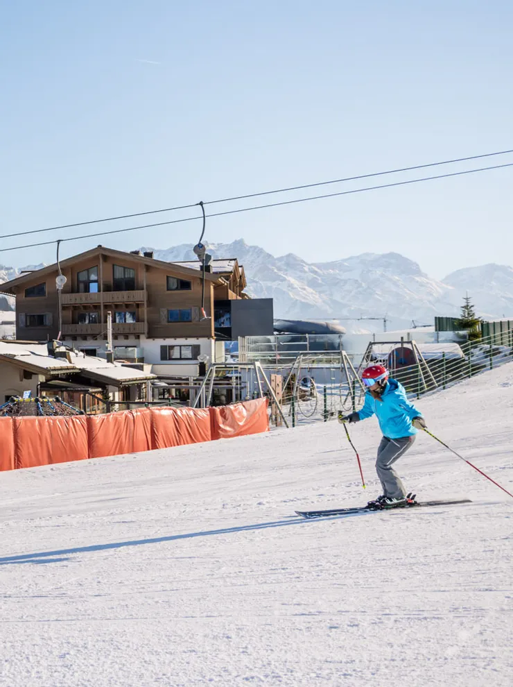 Skier in front of Good Life Resort Leogang with snowy Alps in the background