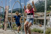 Children balancing on rope obstacle course at outdoor playground in the mountains