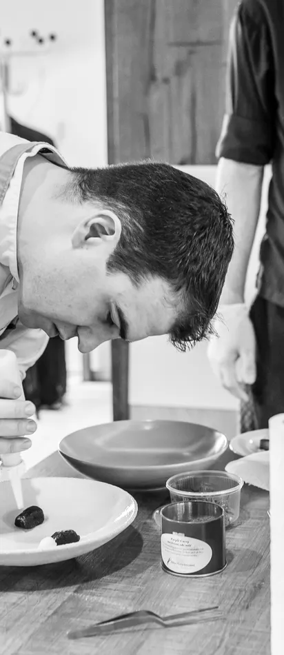 Chef carefully plating gourmet dish in a professional kitchen