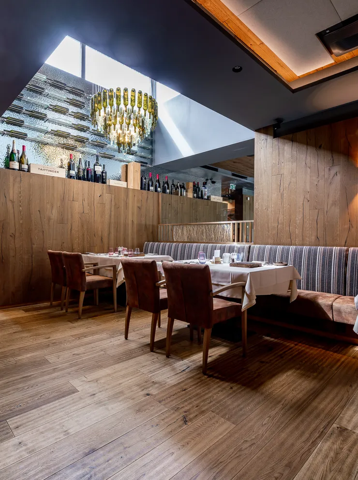 Elegantes Restaurant mit Holzwänden, Weinflaschen und Kronleuchter aus Glasflaschen