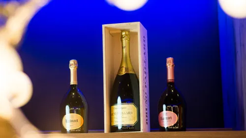 Champagnerflaschen von Ruinart und Bruno Paillard auf einem Regal mit blauem Hintergrund