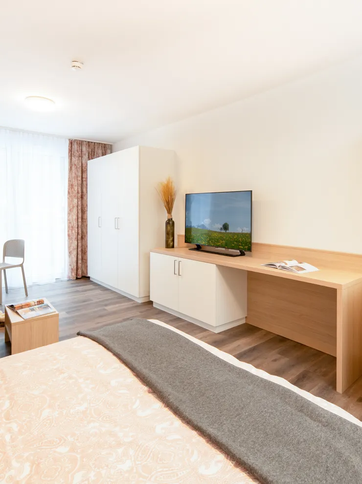 Modern studio apartment with kitchenette, TV, bed and seating area