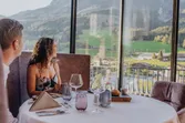 Paar speist in einem eleganten Restaurant mit Blick auf die Berge und stilvoll gedecktem Tisch