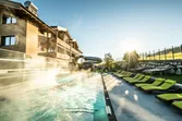 Beheizter Außenpool eines Hotels mit Sonnenliegen und Wasserrutsche bei Sonnenaufgang