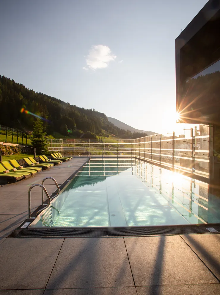 Infinity-Pool im Wellnesshotel mit Blick auf Alpenlandschaft bei Sonnenuntergang