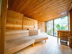 Moderne Holzsauna mit großem Fenster und Bergblick