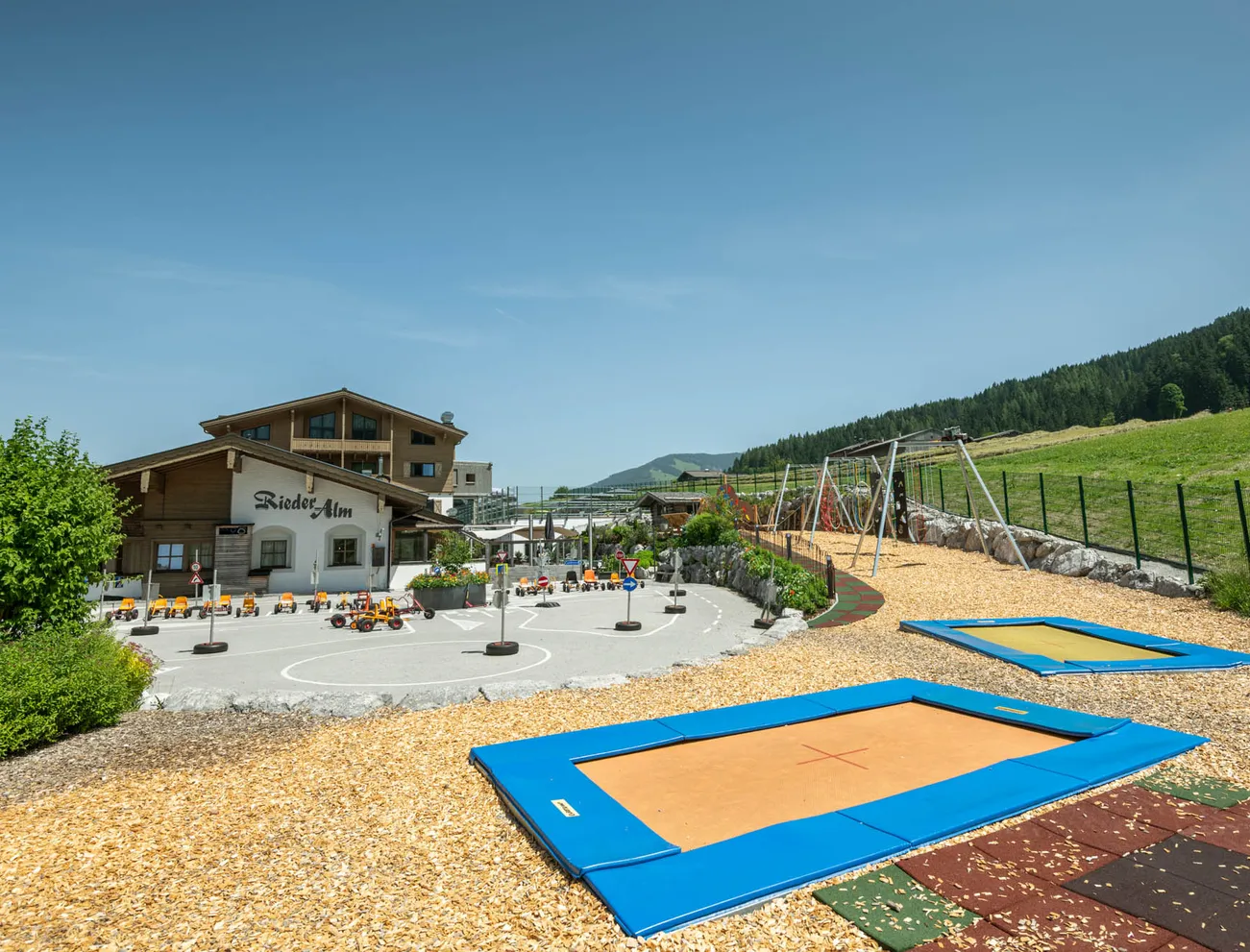 Outdoor-Spielplatz mit Trampolinen, Spielzeugfahrzeugen und Schaukeln bei der Almhütte Rieder Alm