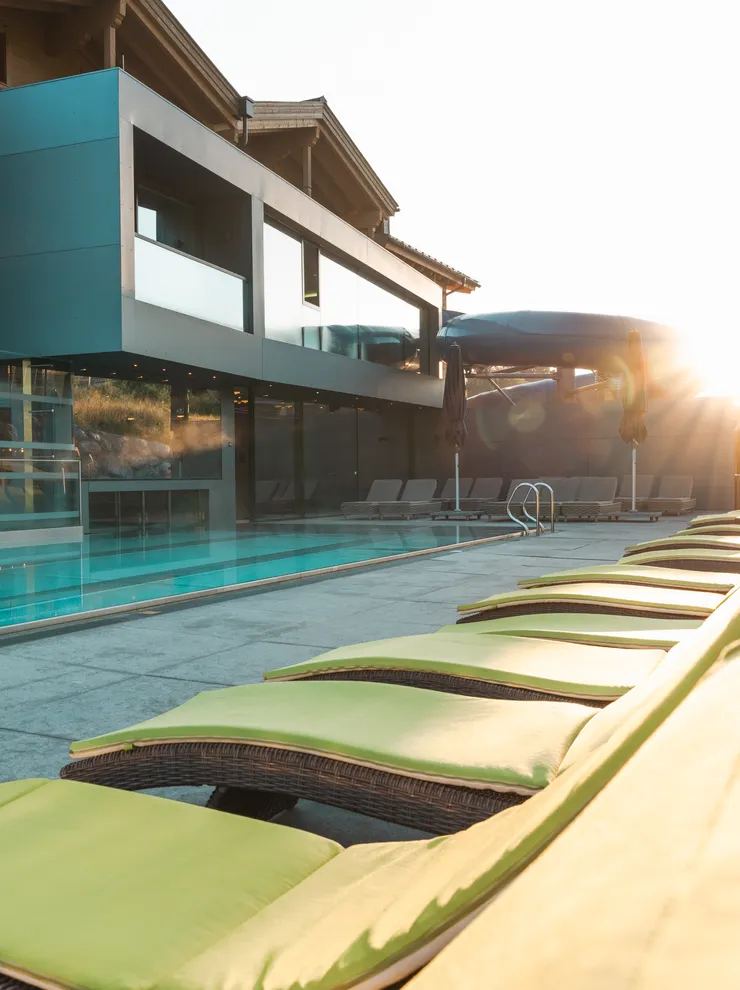 Modern hotel poolside with green loungers and sun umbrellas at sunrise