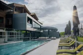 Modern mountain resort with outdoor pool, water slide, and sun loungers on a sunny day