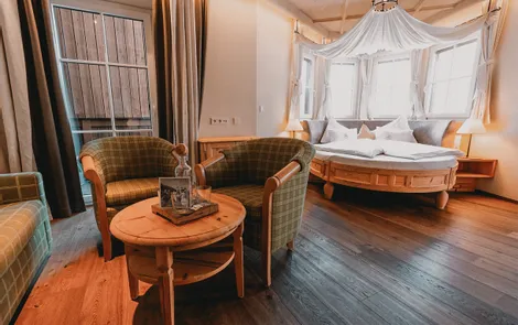 Himmelreich Cozy hotel room with round bed, wooden floor and seating area with two armchairs