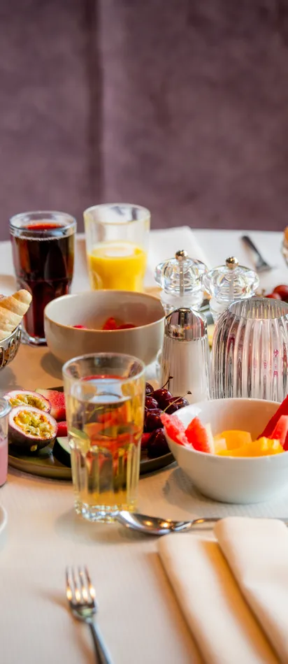 Eleganter Frühstückstisch mit frischem Obst, Gebäck, Saft, Kaffee und Aufschnitt