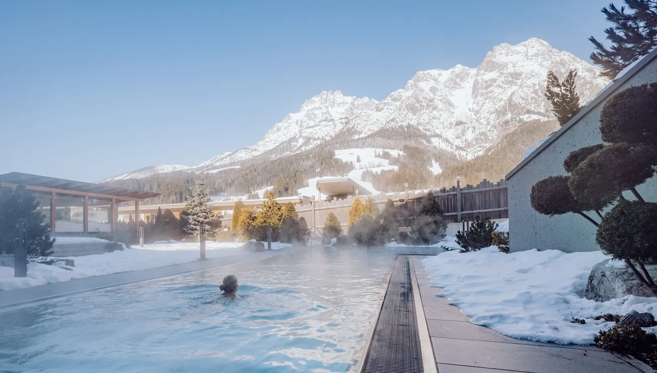Outdoor thermal pool with mountain view and snow-covered surroundings in winter resort