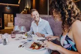 Smiling couple enjoying fine dining with wine in a modern upscale restaurant