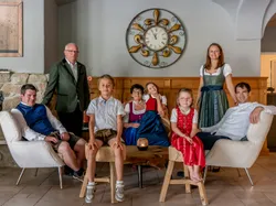Family in traditional Bavarian clothing sitting and standing in cozy living room
