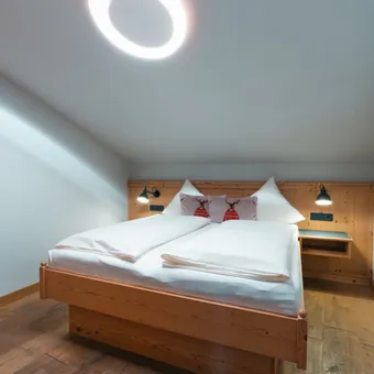 Cozy wooden bedroom with double bed, reindeer pillows, and modern ring ceiling light