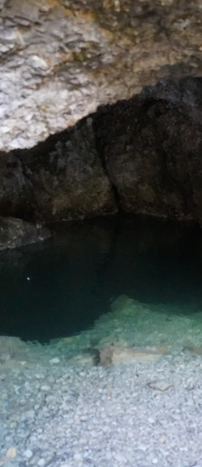 Kleines kristallklares Wasserbecken in einer felsigen Höhle mit Natursteinwänden