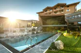 Luxury mountain hotel with outdoor heated pool and sun flare in the Alps