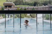 Woman relaxing in an outdoor heated pool with mountain view in luxury spa resort