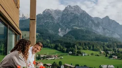Couple in bathrobes enjoying mountain view from balcony in alpine resort