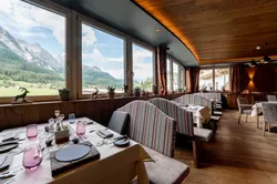 Cozy restaurant with striped booths and panoramic alpine mountain views through large windows