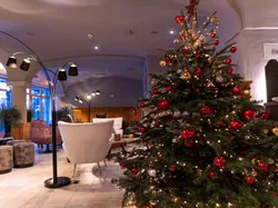 Decorated Christmas tree with red and gold ornaments in cozy hotel lobby