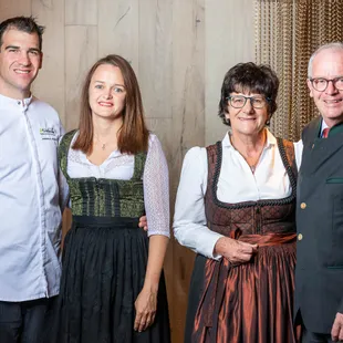 Gruppenporträt von vier Erwachsenen in traditioneller österreichischer Tracht, die drinnen lächeln