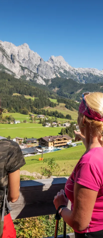 Zwei Frauen beim Wandern in Leogang mit Blick auf ein Alpendorf und ein Bergpanorama