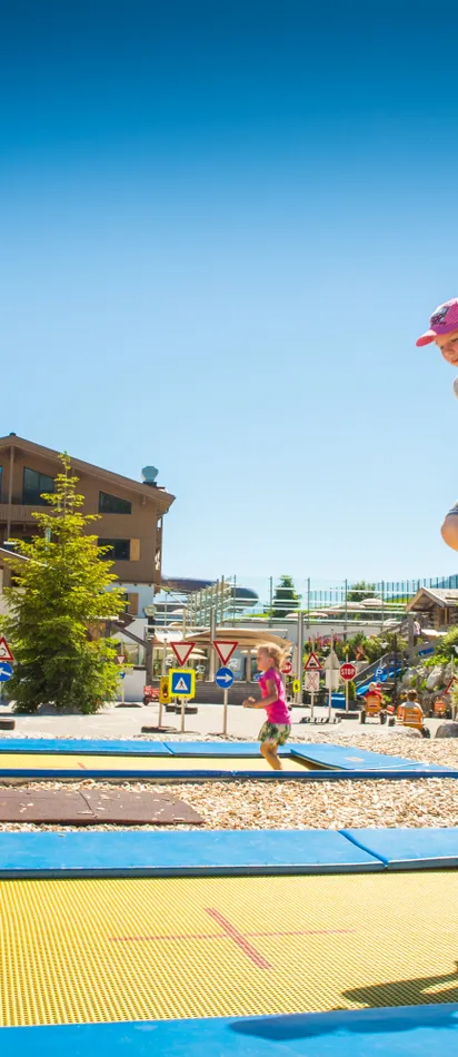 Girl jumping on trampoline in sunny weather at Riederalm alpine resort
