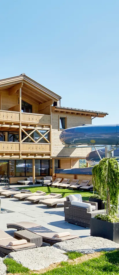 Luxury alpine resort with outdoor pool, sun loungers, and large waterslide