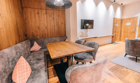 Cozy modern dining area with wooden table, grey chairs, and wood-paneled walls
