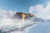 Luxury alpine resort with steaming outdoor pool and snowy mountain backdrop