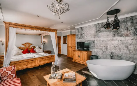 Luxuriöses Hotelzimmer mit Himmelbett, freistehender Badewanne, Holzmöbeln und modernem Dekor