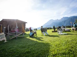 Strohfiguren beim Bauernherbst-Fest auf einer Wiese vor Alpenkulisse