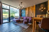 Modern hotel room with purple sofa, wooden decor, and mountain view from balcony