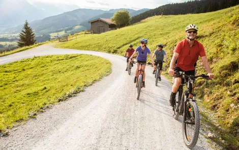 Group of cyclists riding mountain bikes on a gravel path through scenic countryside