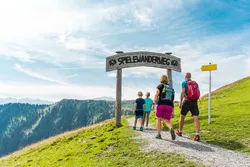 Family hiking on the Spielewanderweg trail in the Alps under sunny skies