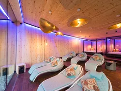 Modern spa relaxation room with cushioned loungers, wood walls, and ambient lighting