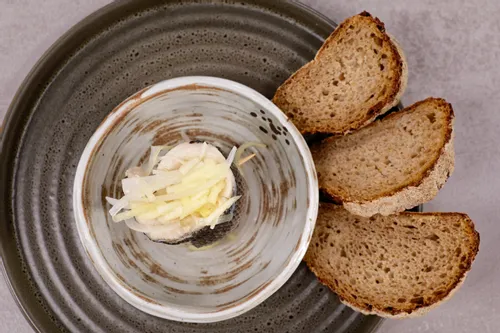 Gerollter eingelegter Hering mit Zwiebeln und Apfelstreifen, serviert mit Brotscheiben